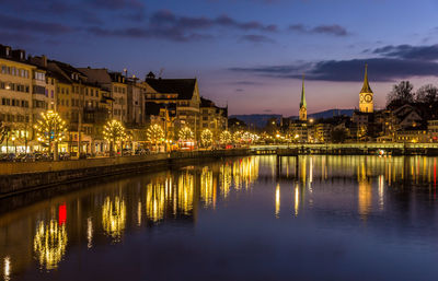 Reflection of illuminated buildings in city at waterfront