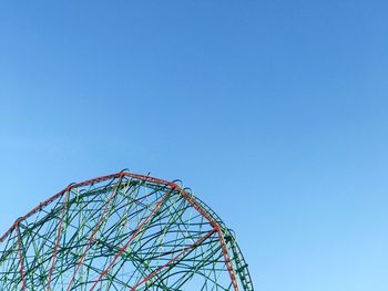 Low angle view of ferris wheel against clear blue sky