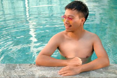 Portrait of shirtless man swimming in pool