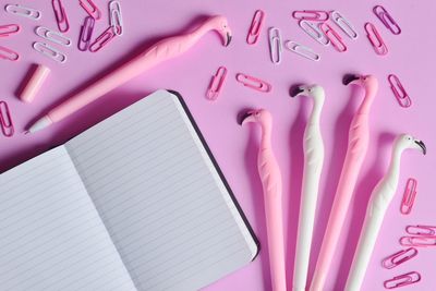 Directly above shot of note pad and pencils over pink background