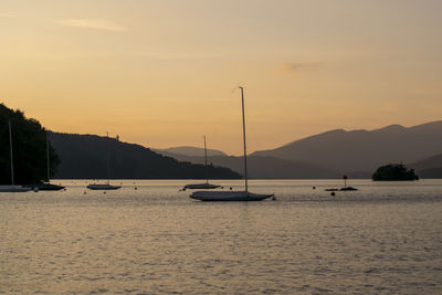 Sailboats in sea against sky during sunset