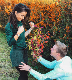 Full length of smiling girl holding plant during autumn