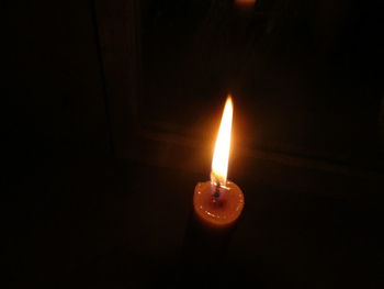 Close-up of illuminated candle in darkroom