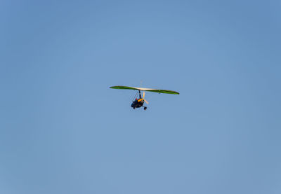 Low angle view of air vehicle flying against clear blue sky