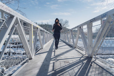 Attractive young brunette woman running through the city after a big snow storm