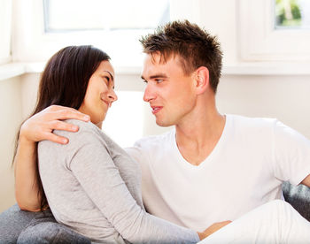 Young couple romancing while sitting on sofa at home