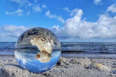 Crystal ball with stuffed toy reflection on sandy beach