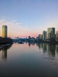 Buildings by river against sky in city