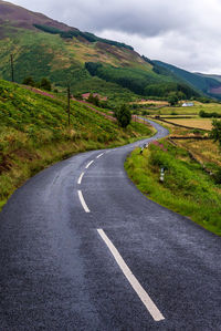 Road amidst green landscape against sky