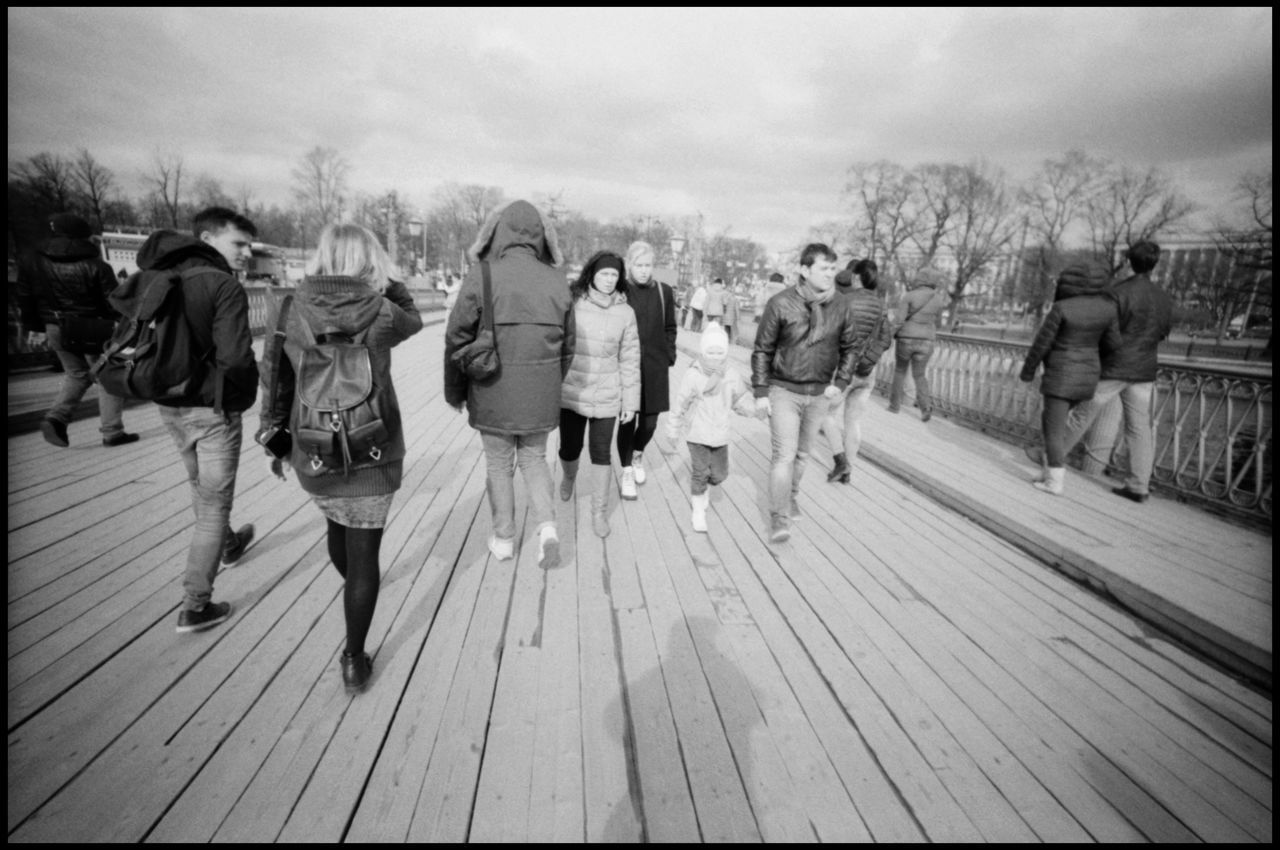 REAR VIEW OF PEOPLE WALKING ON WOODEN PIER