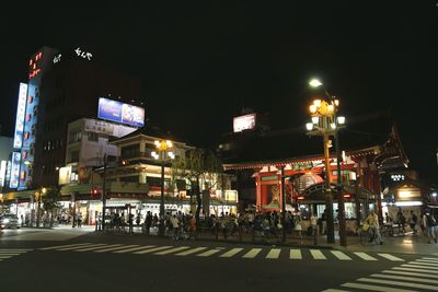 Illuminated city street against sky at night