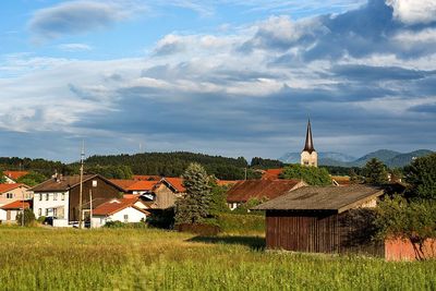 Houses on field against cloudy sky