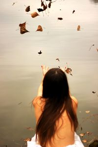 Rear view of woman with birds flying over water