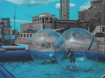 Digital composite image of people in swimming pool against buildings in city