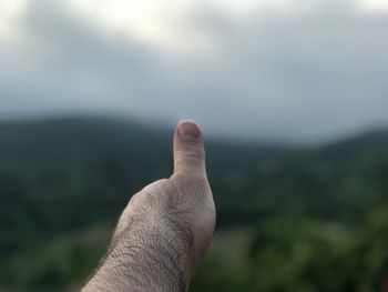 Cropped hand showing thumbs up against sky