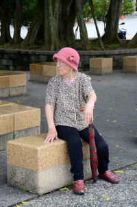 Full length of woman wearing hat while sitting against trees