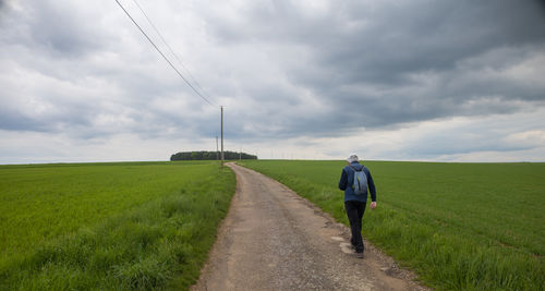 Rear view of man walking on dirt road