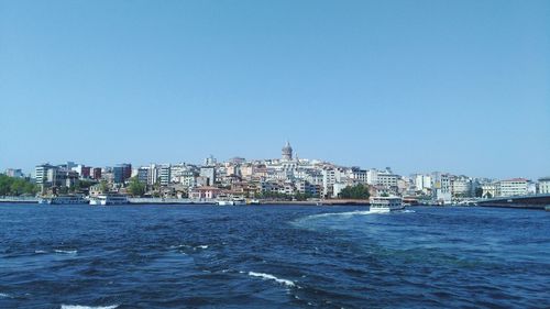 View of buildings in city against clear blue sky