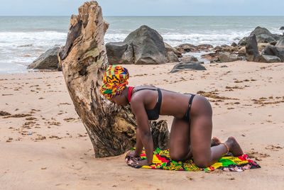 Midsection of woman sitting on shore at beach