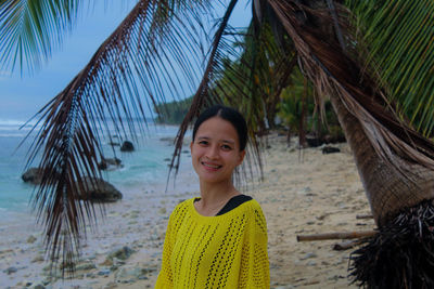 Portrait of young woman standing against palm trees