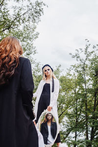 Woman holding mirror with reflection of female model at park