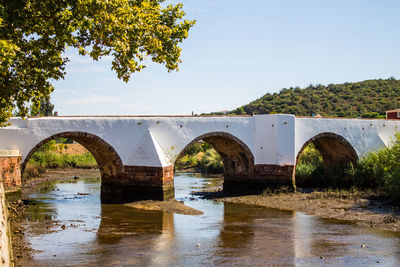 Arch bridge over river against sky