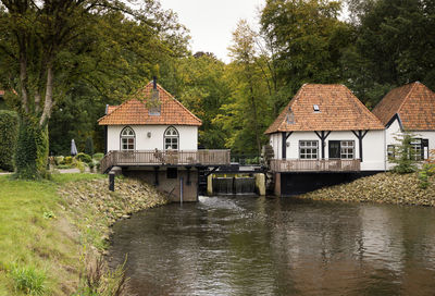 House by river amidst trees and plants