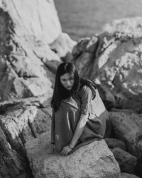 Young woman sitting on rock formation at beach