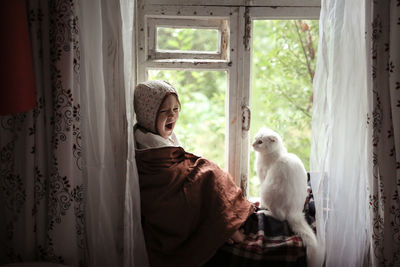 Magical photo of a child toddler with a cat sitting on the window, the concept of favorite animals