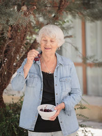 Elderly woman holding a bowl of ripe cherries