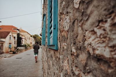 Rear view of man walking by building in city