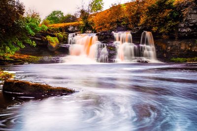 Scenic view of waterfall in forest against sky