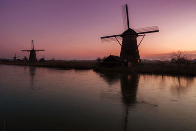 Traditional windmill on field during sunset