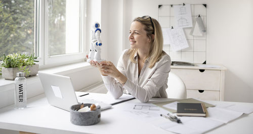 Woman looking at camera while sitting on table