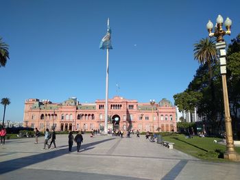 People walking in historic building against clear sky