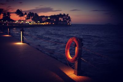 Inflatable ring on fence at pier over sea against sky