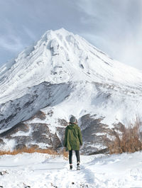 Rear view of woman standing by snow covered mountain against sky