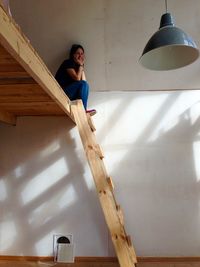 Low angle view of young woman sitting on bunkbed