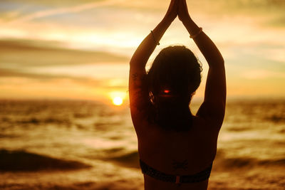 Midsection of woman at beach during sunset