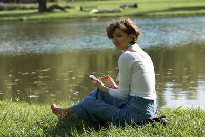 Side view of young woman standing by lake