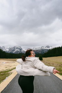 Rear view of woman standing on field against sky