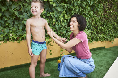 A mother puts sun cream on her son.