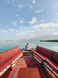 Rear view of man sitting on boat against sea