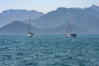 Sailboats on sea against mountains