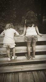 Rear view of mother with daughter standing against trees