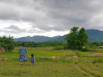 Rear view of mother and daughter walking on land
