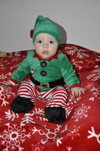 Full length portrait of baby boy wearing elf costume on bed at home