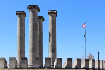 Low angle view of flags against clear blue sky