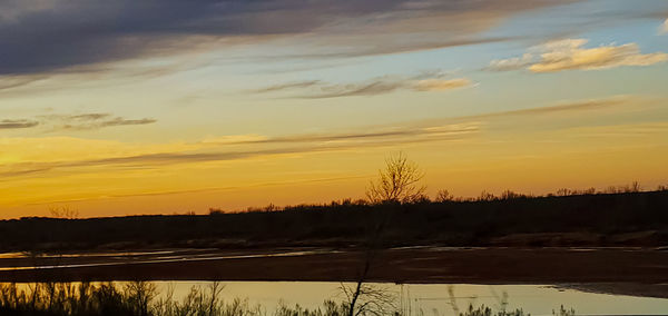 Scenic view of lake against orange sky during sunset