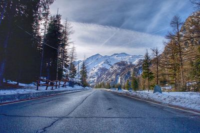 Road amidst trees against sky during winter